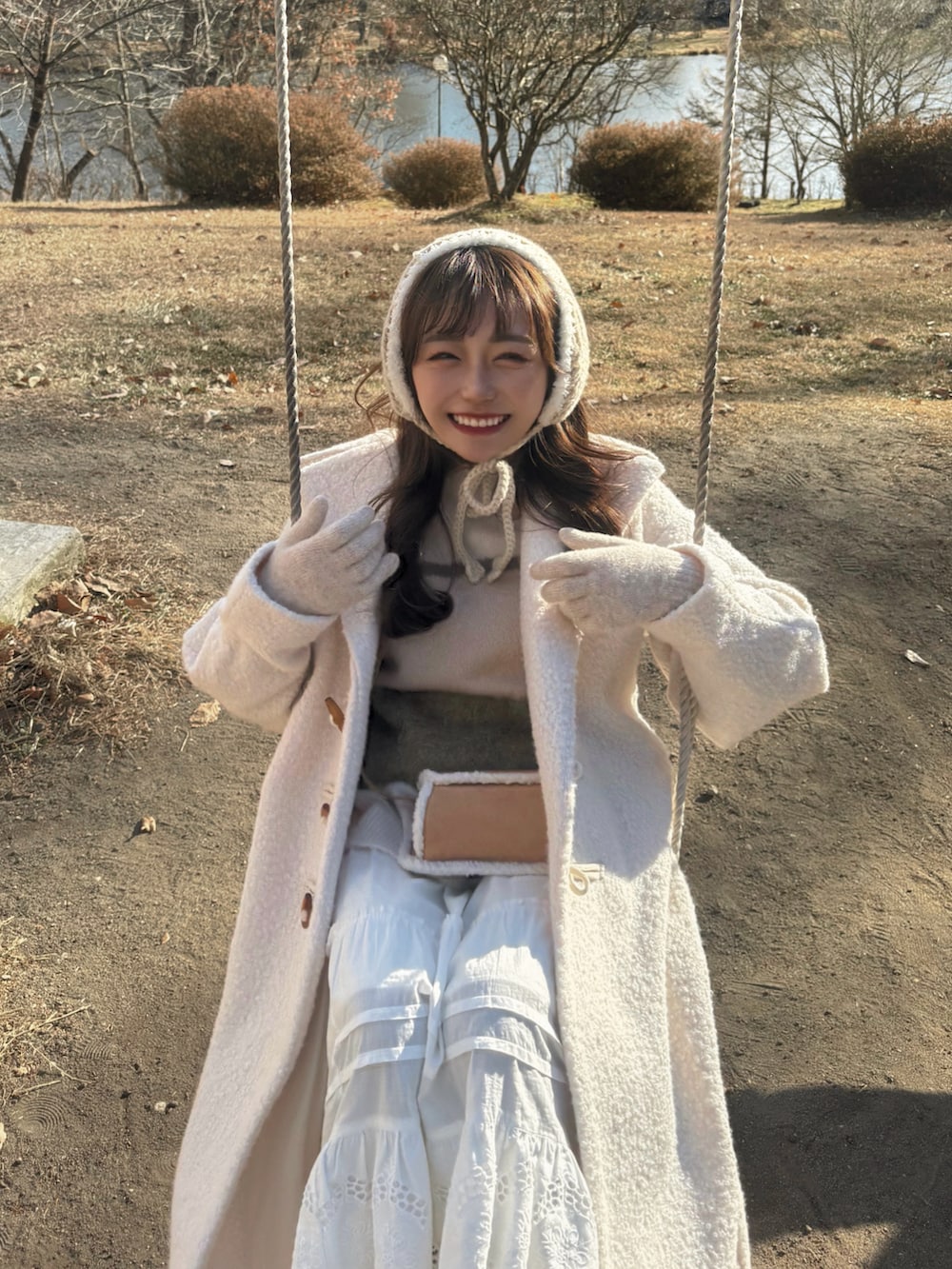 ホワイト系のジャケット/アウター、ブラウン系のショルダーバッグ、ホワイト系のニット/セーターを着用したレディースの冬コーディネートの3枚目の写真