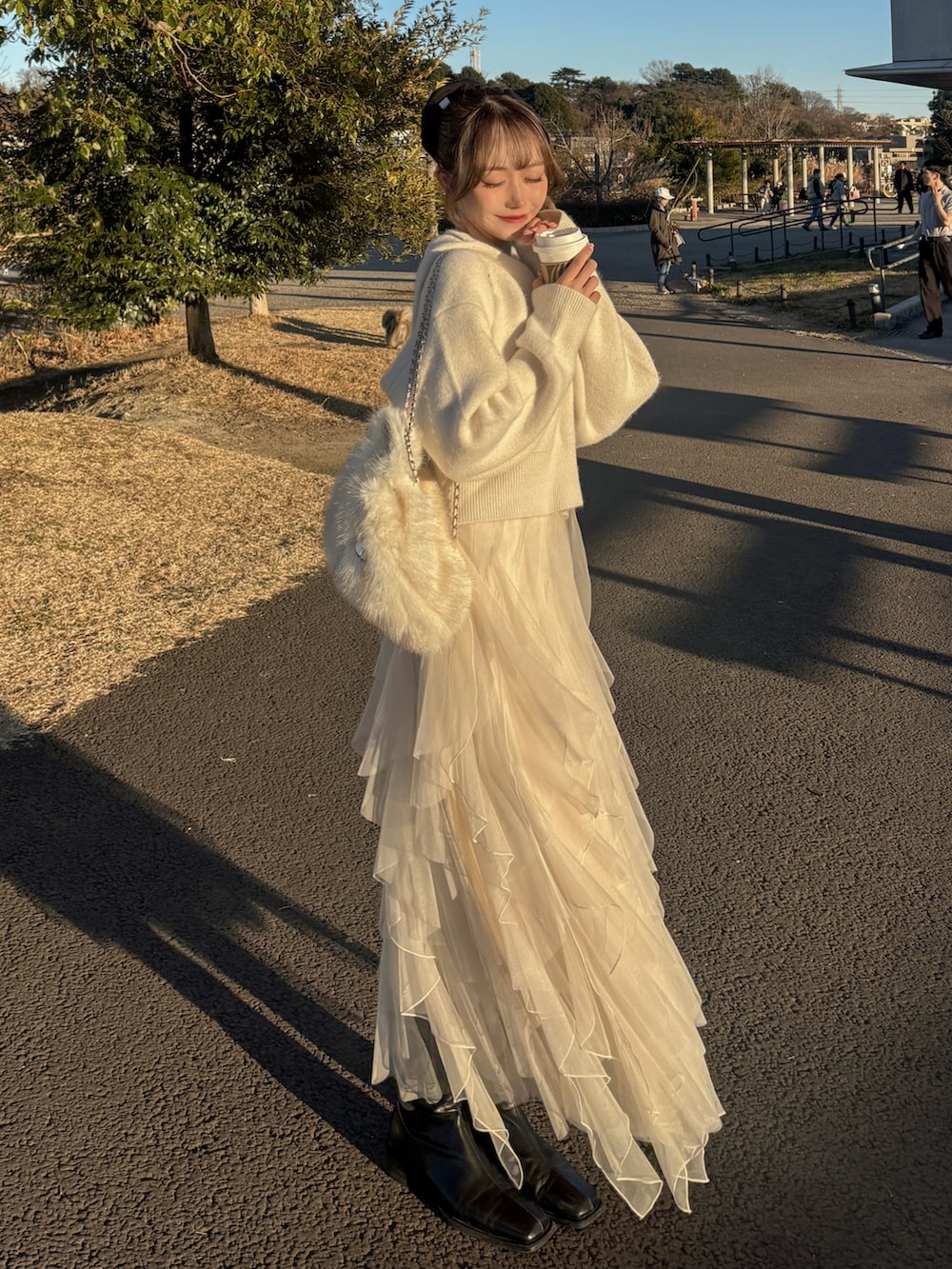 ホワイト系のニット/セーター、ホワイト系のスカート、ブラック系のブーツを着用したレディースの冬コーディネートの4枚目の写真