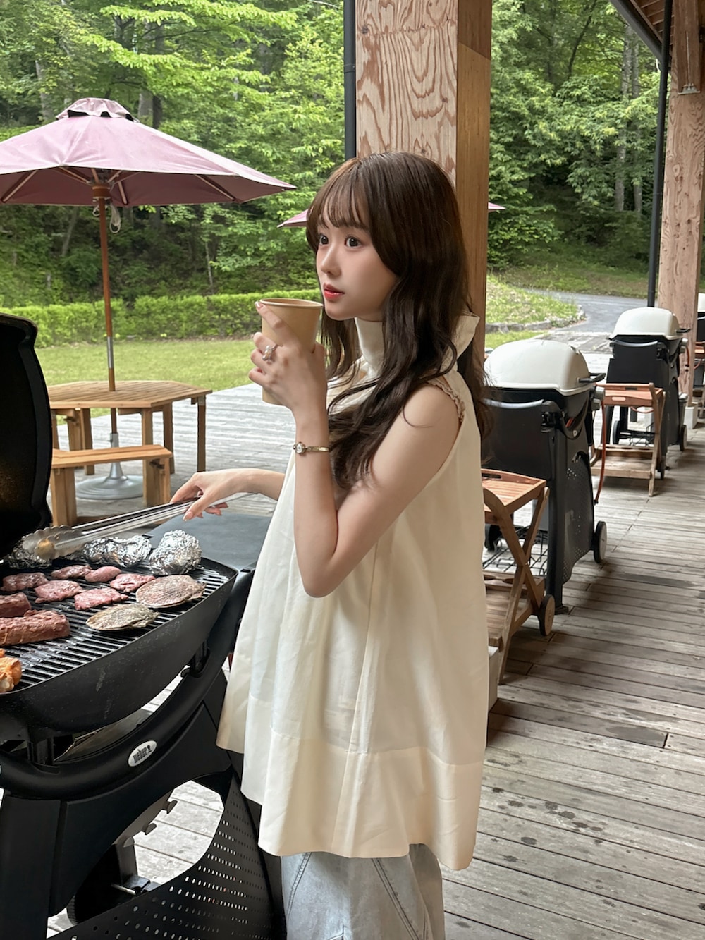 ブルー系のデニムパンツ、ホワイト系のシャツ/ブラウス、ブラック系のかごバッグを着用したレディースの夏コーディネートの2枚目の写真