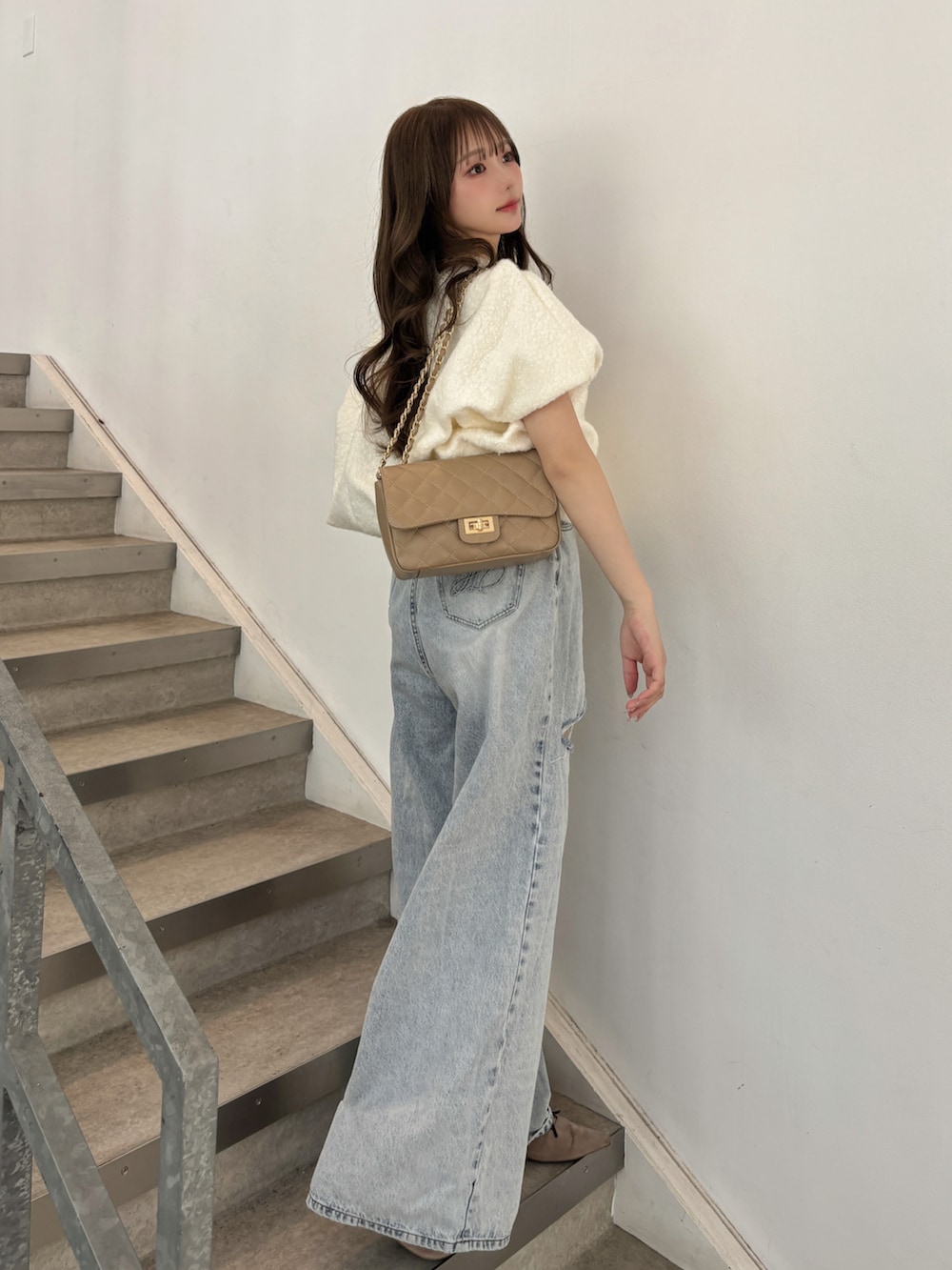 ブルー系のデニムパンツ、ベージュ系のショルダーバッグ、ベージュ系のパンプスを着用したレディースの秋コーディネートの2枚目の写真