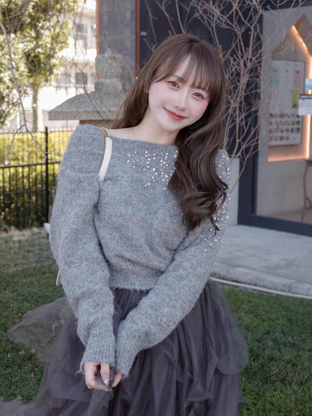 グレー系のパンプス、グレー系のニット/セーター、グレー系のスカートを着用したレディースの春コーディネートの2枚目の写真