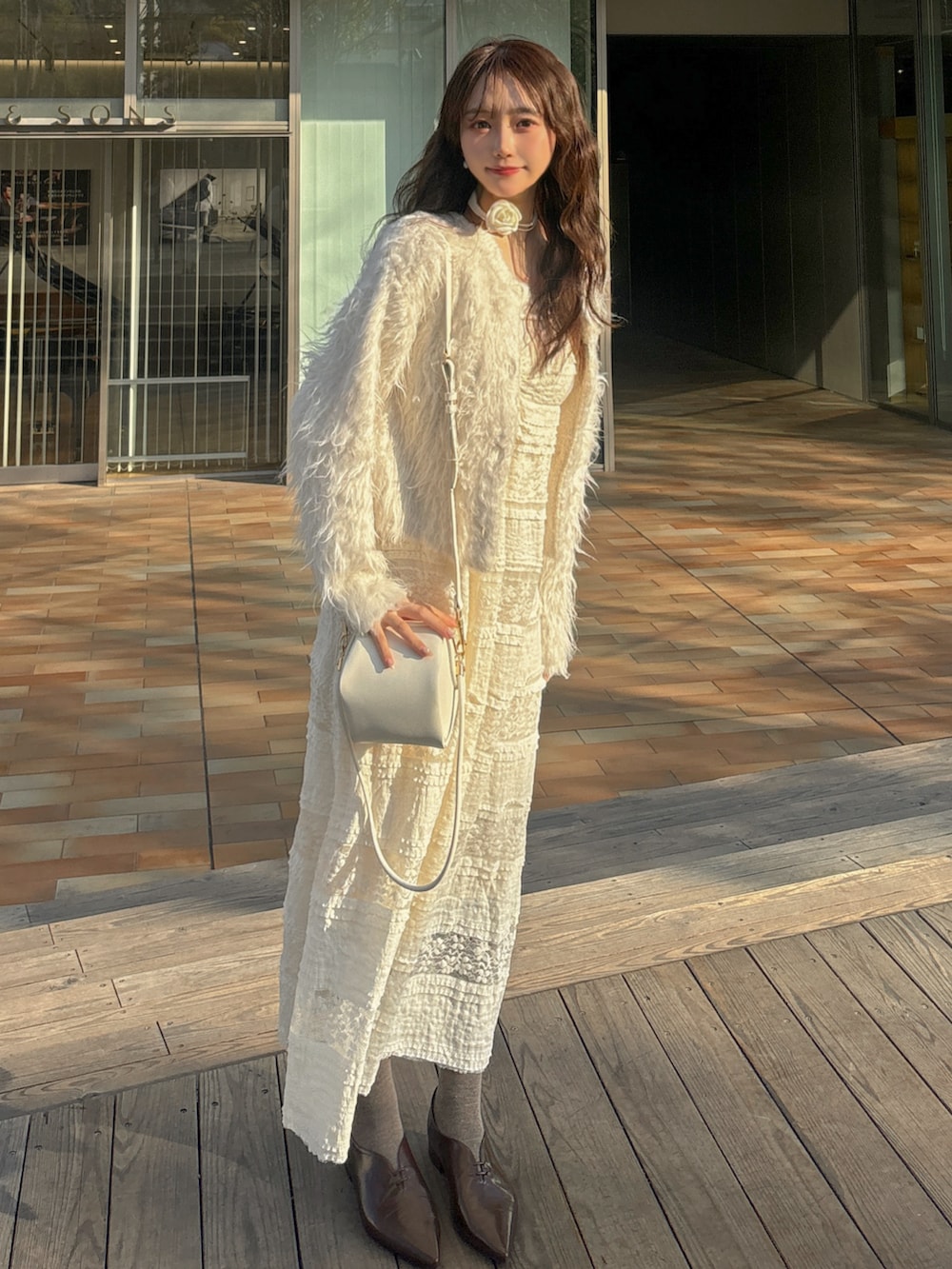 ベージュ系のショルダーバッグ、ホワイト系のワンピース、ホワイト系のカーディガン/ボレロを着用したレディースの春コーディネートの2枚目の写真