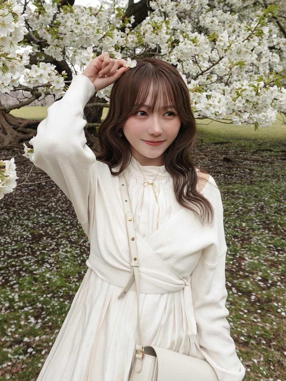 ホワイト系のスカート、ホワイト系のニット/セーター、ホワイト系のバッグを着用したレディースの春コーディネートの5枚目の写真