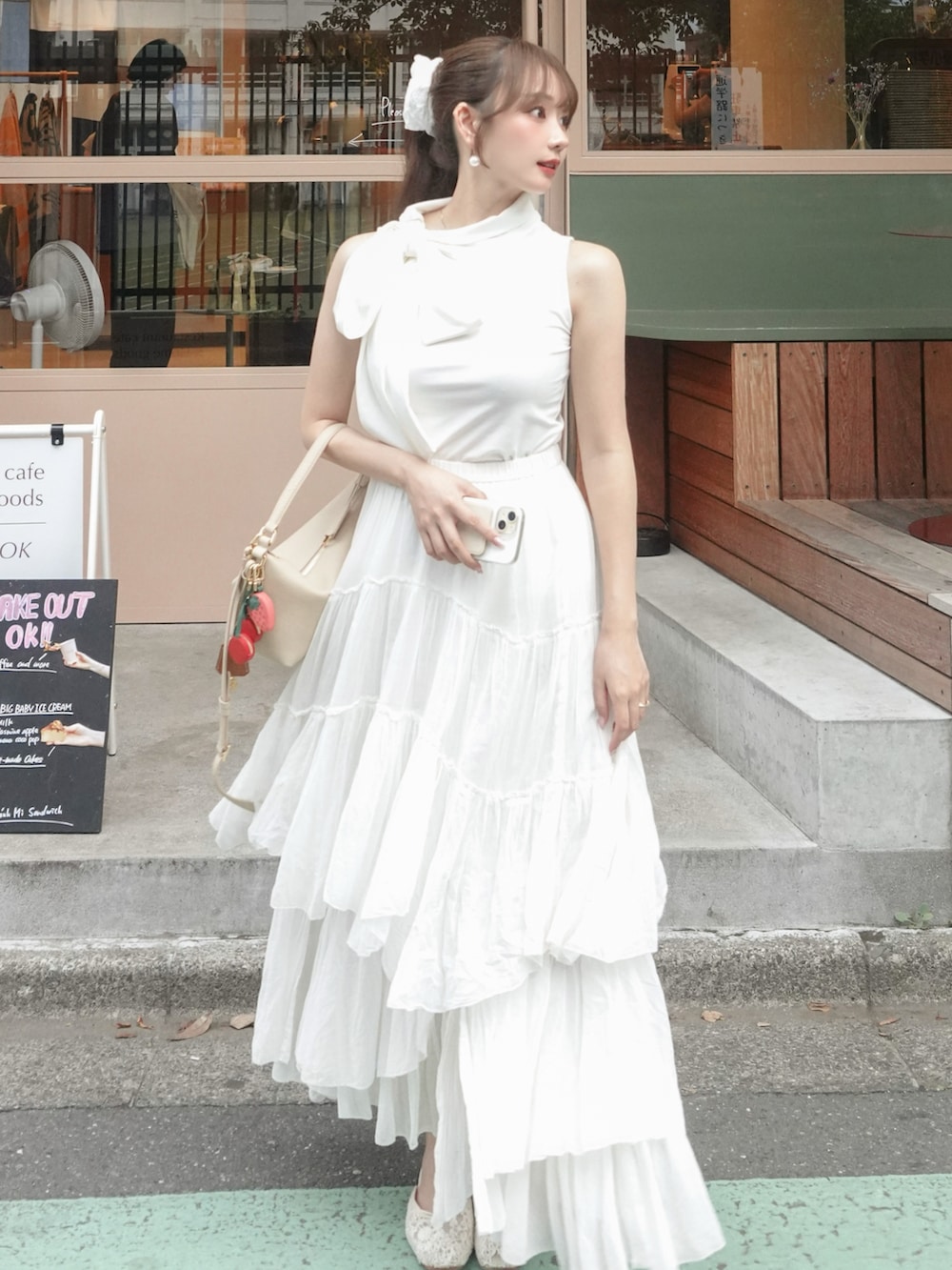 ホワイト系のスカート、ホワイト系のトップス、ベージュ系のバッグを着用したレディースの夏コーディネートの2枚目の写真
