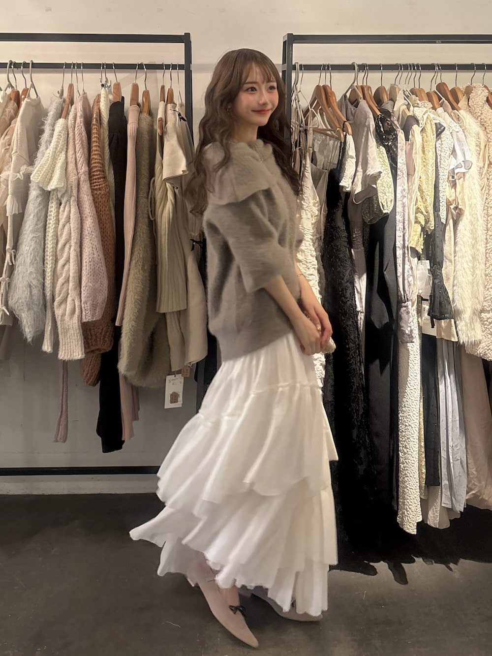 ゴールド系のバッグ、ブラウン系のニット/セーター、ホワイト系のスカートを着用したレディースの秋コーディネートの2枚目の写真