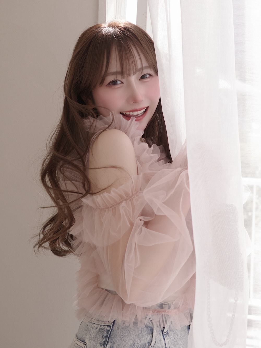 ピンク系のトップス、ゴールド系のバッグ、ブルー系のパンツを着用したレディースの春コーディネートの2枚目の写真