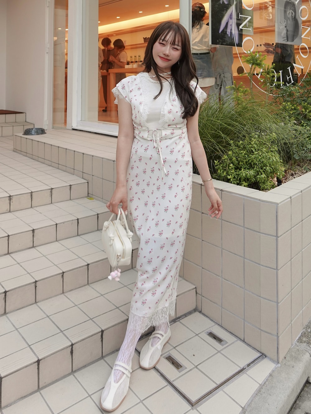 ピンク系のワンピース、ホワイト系のキャミソール、ベージュ系のトートバッグを着用したレディースの夏コーディネートの2枚目の写真