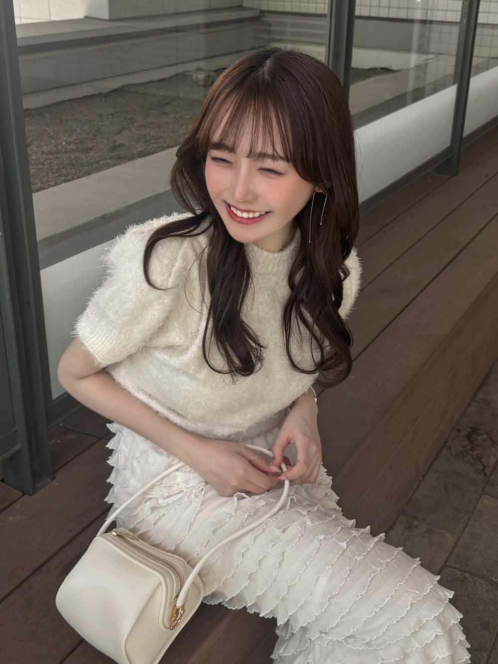 ホワイト系のニット/セーター、ホワイト系のスカート、ブラック系のパンプスを着用したレディースの春コーディネートの2枚目の写真