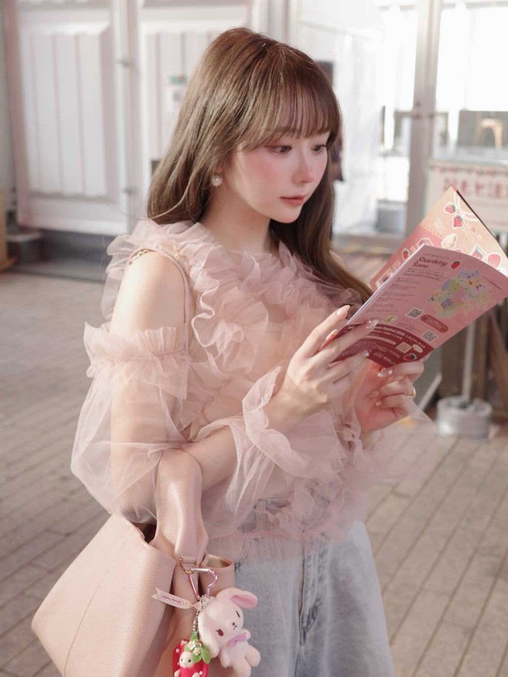 ブルー系のデニムパンツ、ピンク系のトップス、ピンク系のバッグを着用したレディースの冬コーディネートの4枚目の写真