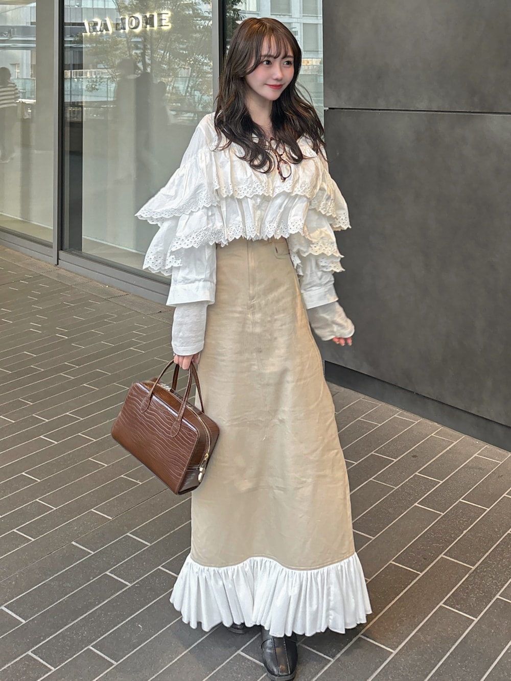 ベージュ系のスカート、ホワイト系のシャツ/ブラウス、ホワイト系のTシャツ/カットソーを着用したレディースの春コーディネートの2枚目の写真