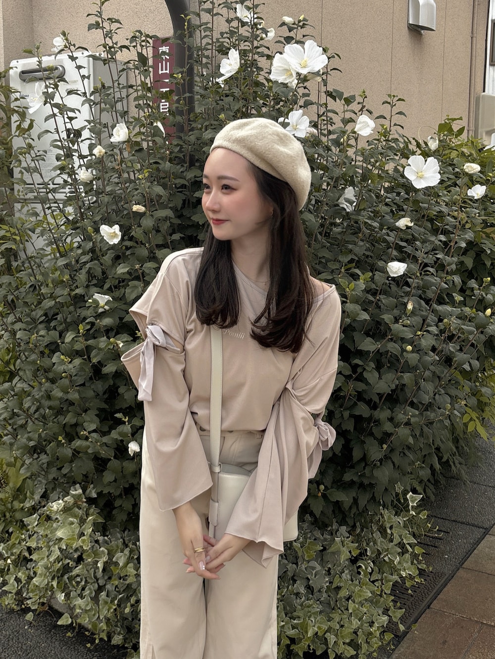 ホワイト系のスラックス、ホワイト系のスニーカー、ホワイト系のバッグを着用したレディースの秋コーディネートの4枚目の写真