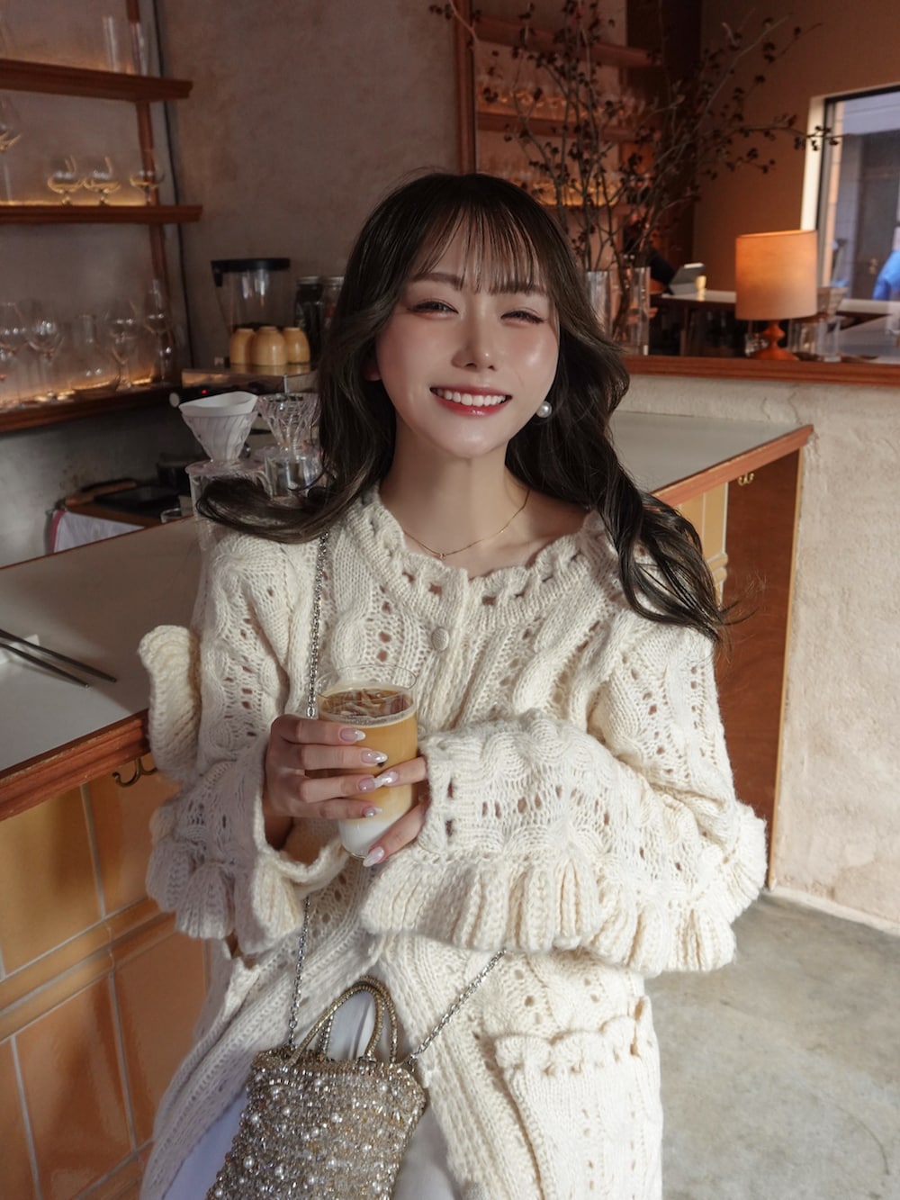 ホワイト系のトップス、ゴールド系のバッグ、ホワイト系のスラックスを着用したレディースの冬コーディネートの4枚目の写真