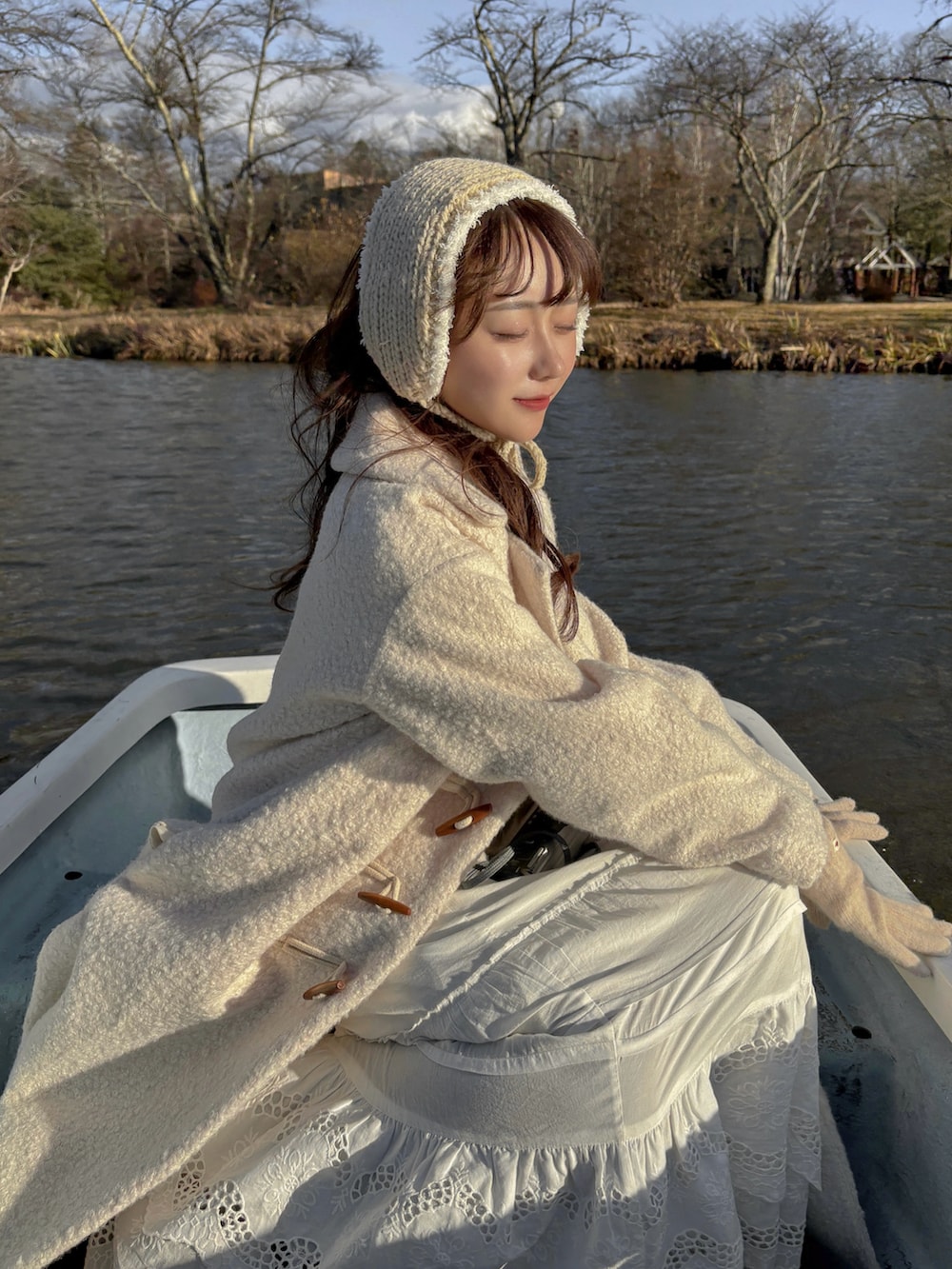 ホワイト系のジャケット/アウター、ブラウン系のショルダーバッグ、ホワイト系のニット/セーターを着用したレディースの冬コーディネートの2枚目の写真