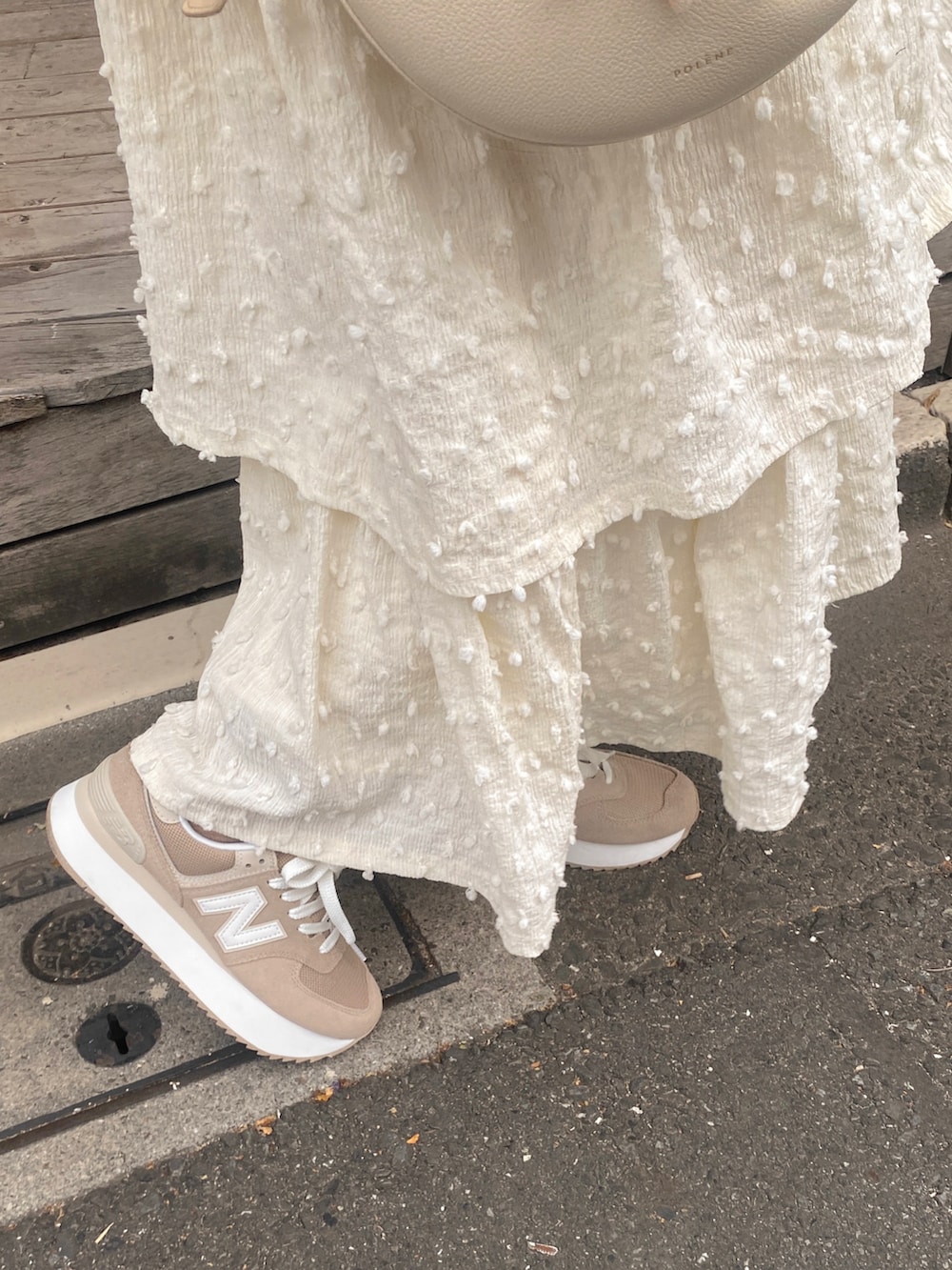 ホワイト系のワンピース、ホワイト系のバッグ、ブラウン系のスニーカーを着用したレディースの秋コーディネートの2枚目の写真