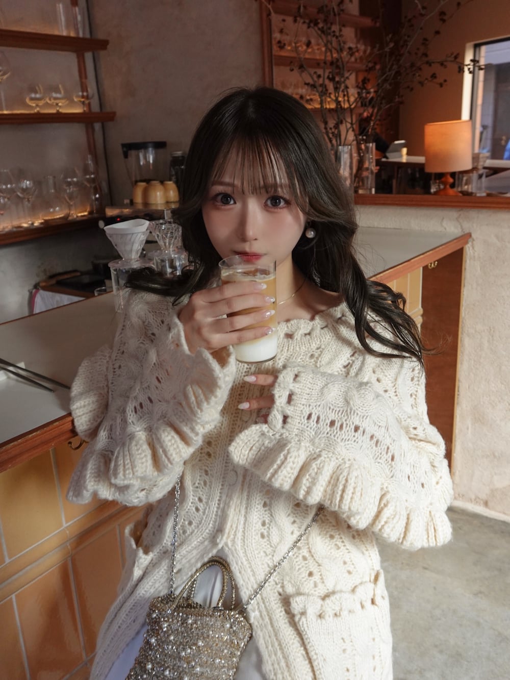 ホワイト系のトップス、ゴールド系のバッグ、ホワイト系のスラックスを着用したレディースの冬コーディネートの3枚目の写真