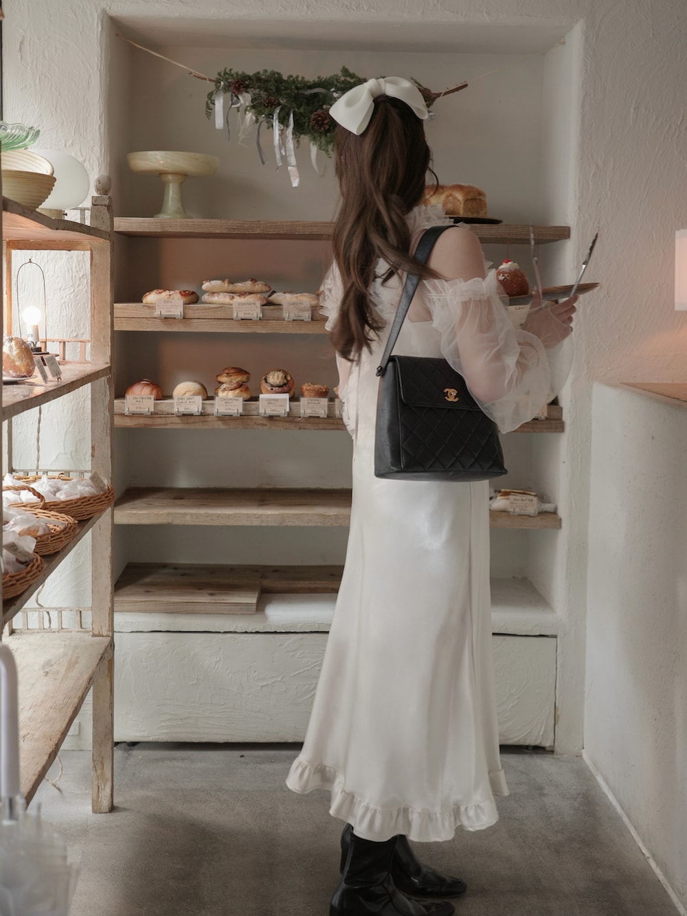 ブラック系のブーツ、ホワイト系のスカート、ホワイト系のトップスを着用したレディースの冬コーディネートの2枚目の写真