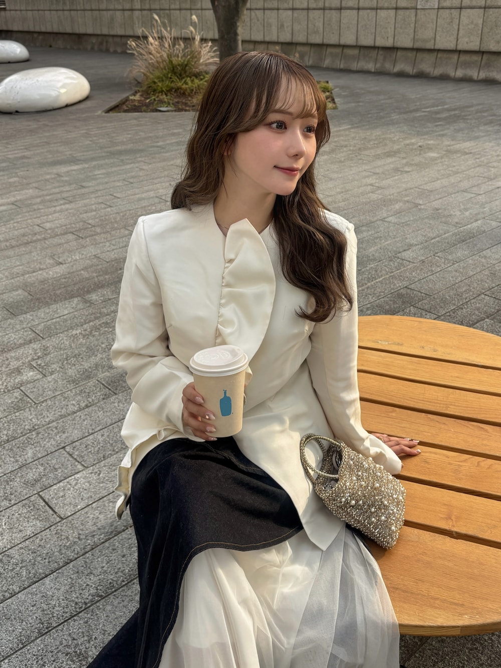 ベージュ系のブーツ、ゴールド系のバッグ、ホワイト系のトップスを着用したレディースの春コーディネートの5枚目の写真