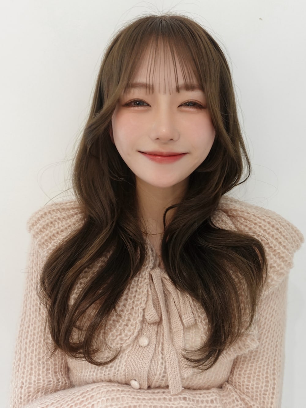 ベージュ系のブーツ、ピンク系のニット/セーター、ホワイト系のスラックスを着用したレディースの春コーディネートの3枚目の写真