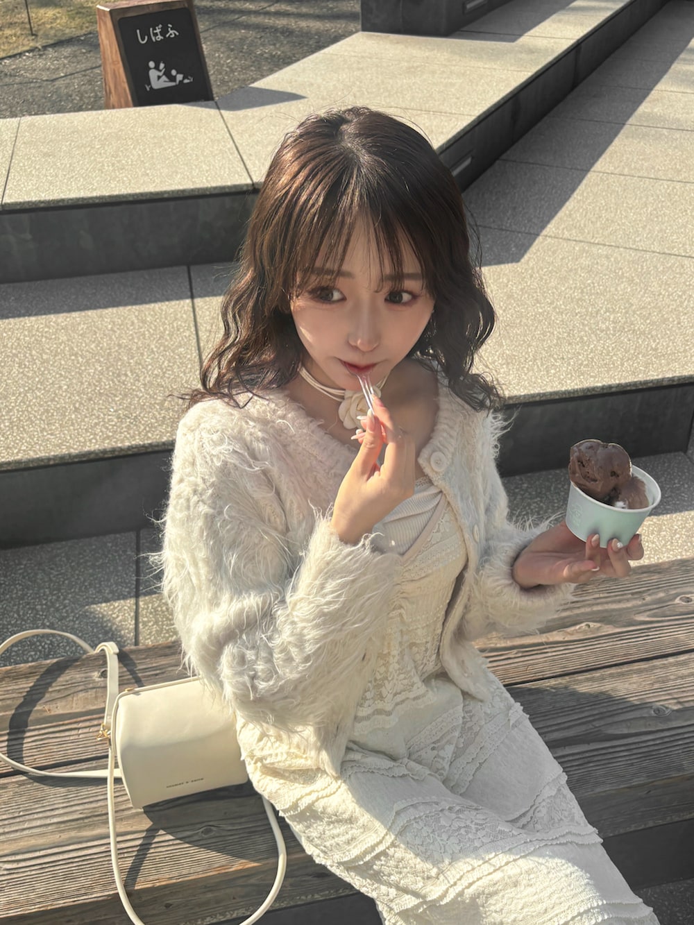 ベージュ系のショルダーバッグ、ホワイト系のワンピース、ホワイト系のカーディガン/ボレロを着用したレディースの春コーディネートの5枚目の写真