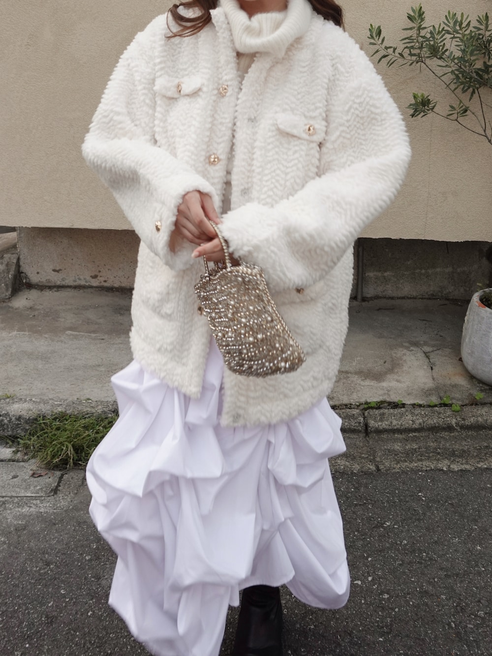 ホワイト系のブルゾン、ホワイト系のスカート、ブラック系のブーツを着用したレディースの秋コーディネートの2枚目の写真