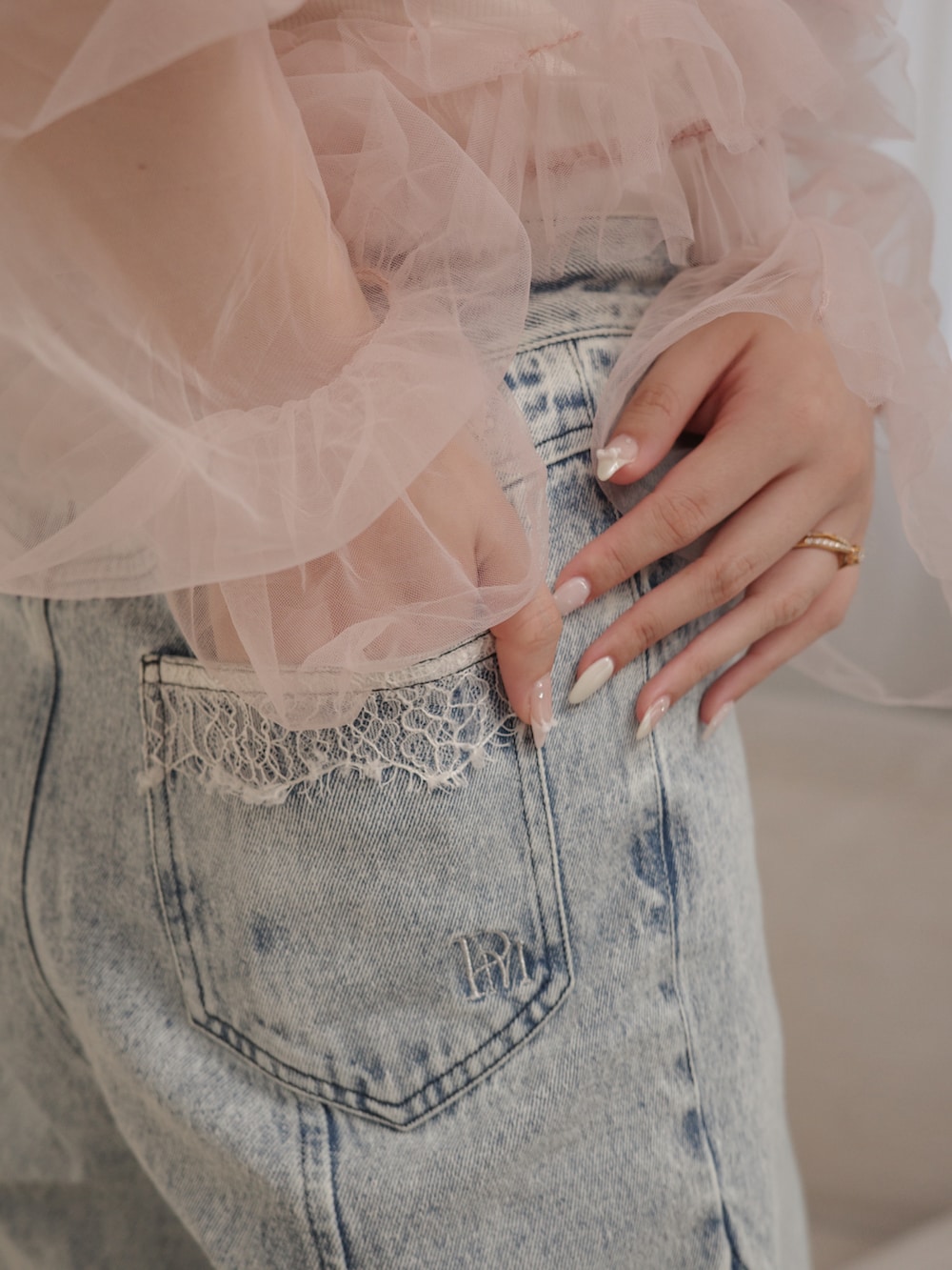 ピンク系のトップス、ゴールド系のバッグ、ブルー系のパンツを着用したレディースの春コーディネートの4枚目の写真