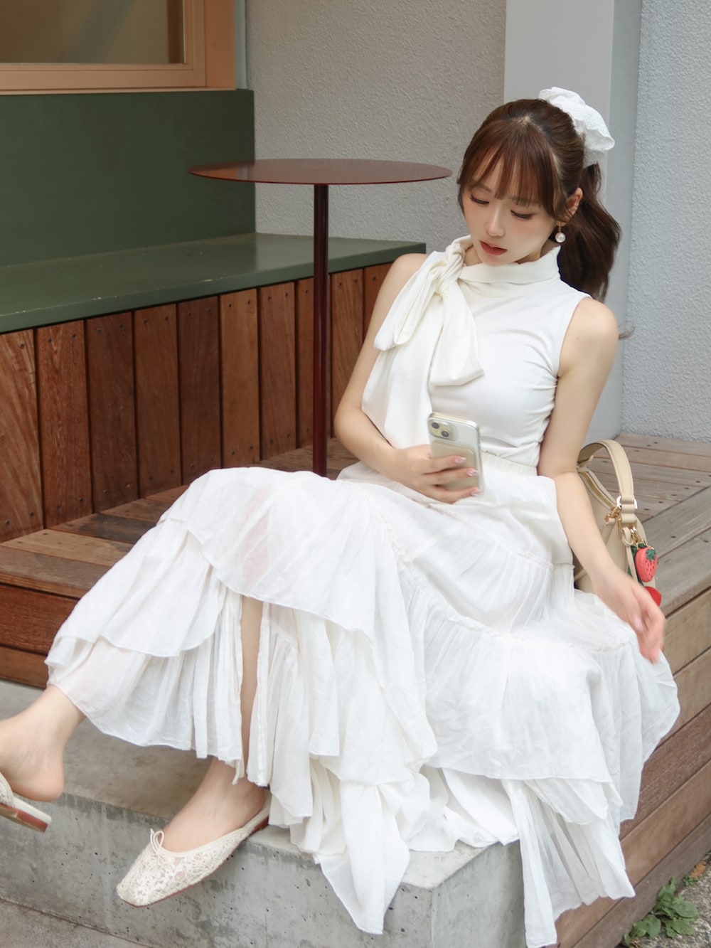 ホワイト系のスカート、ホワイト系のトップス、ベージュ系のバッグを着用したレディースの夏コーディネートの4枚目の写真