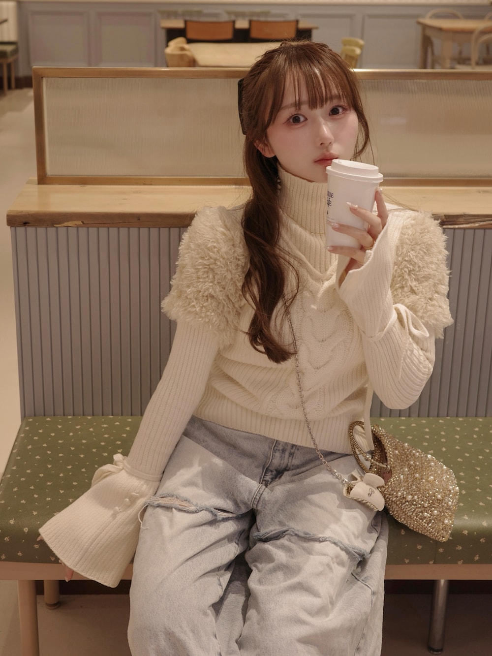 ブルー系のデニムパンツ、ホワイト系のトップス、ゴールド系のバッグを着用したレディースの冬コーディネートの3枚目の写真