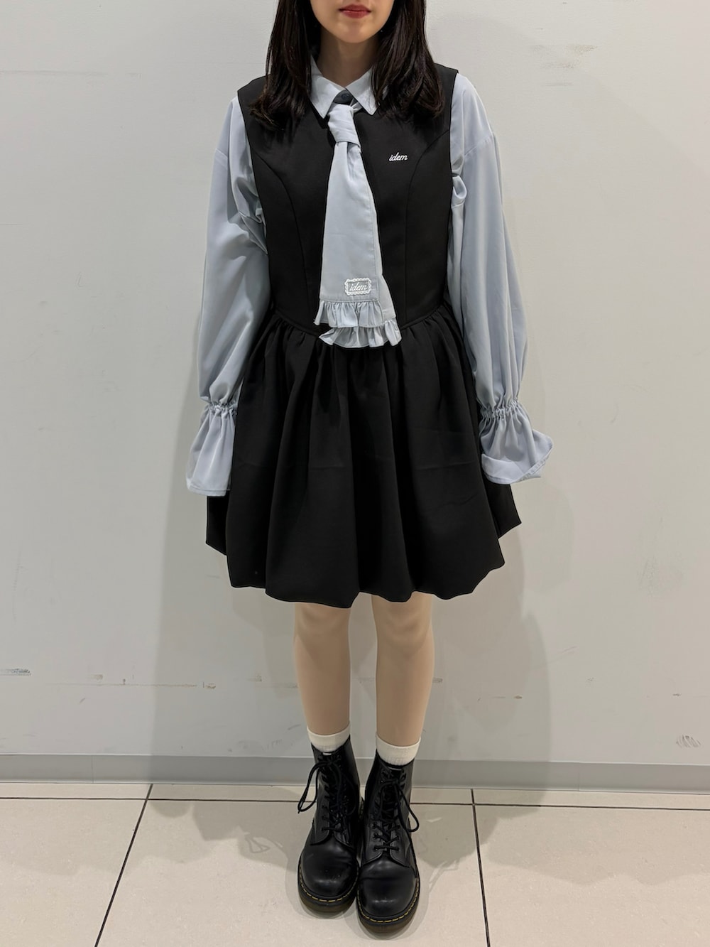 ブラック系のテーラードジャケット、ブルー系のシャツ/ブラウス、ブラック系のジャンパースカートを着用したレディースの春コーディネートの2枚目の写真