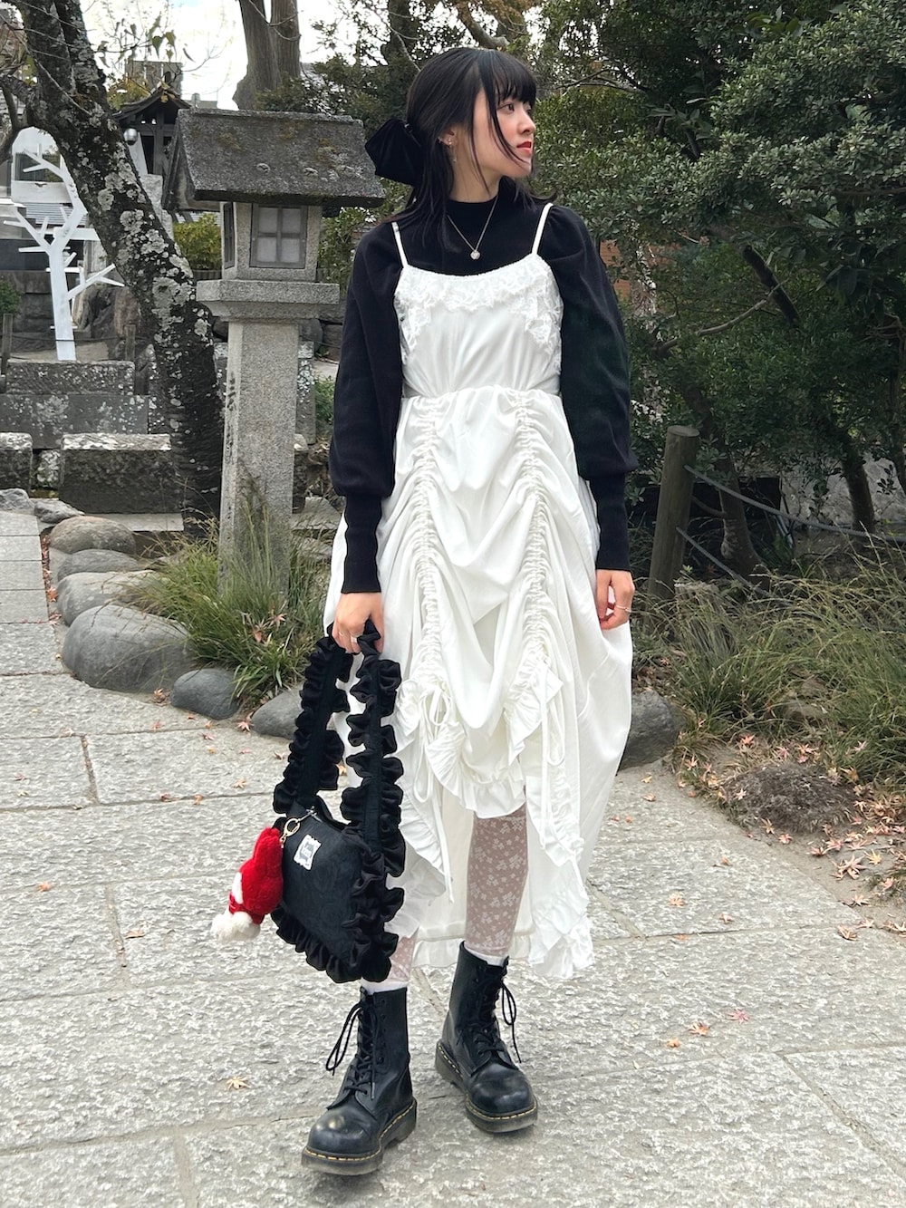 ブラック系のブーツ、ホワイト系のワンピース、ホワイト系のショルダーバッグを着用したレディースの冬コーディネートの3枚目の写真