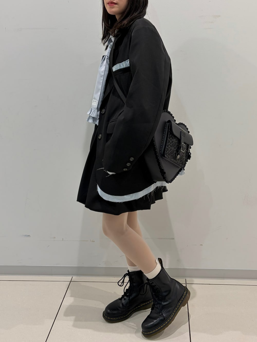 ブラック系のテーラードジャケット、ブルー系のシャツ/ブラウス、ブラック系のジャンパースカートを着用したレディースの春コーディネートの3枚目の写真