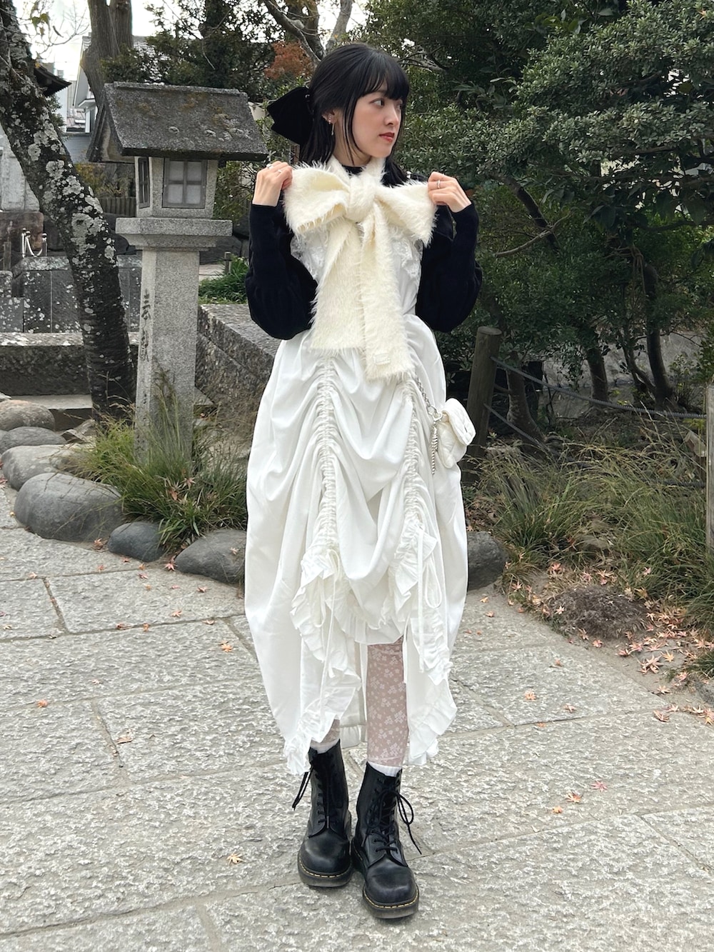 ブラック系のブーツ、ホワイト系のワンピース、ホワイト系のショルダーバッグを着用したレディースの冬コーディネートの2枚目の写真