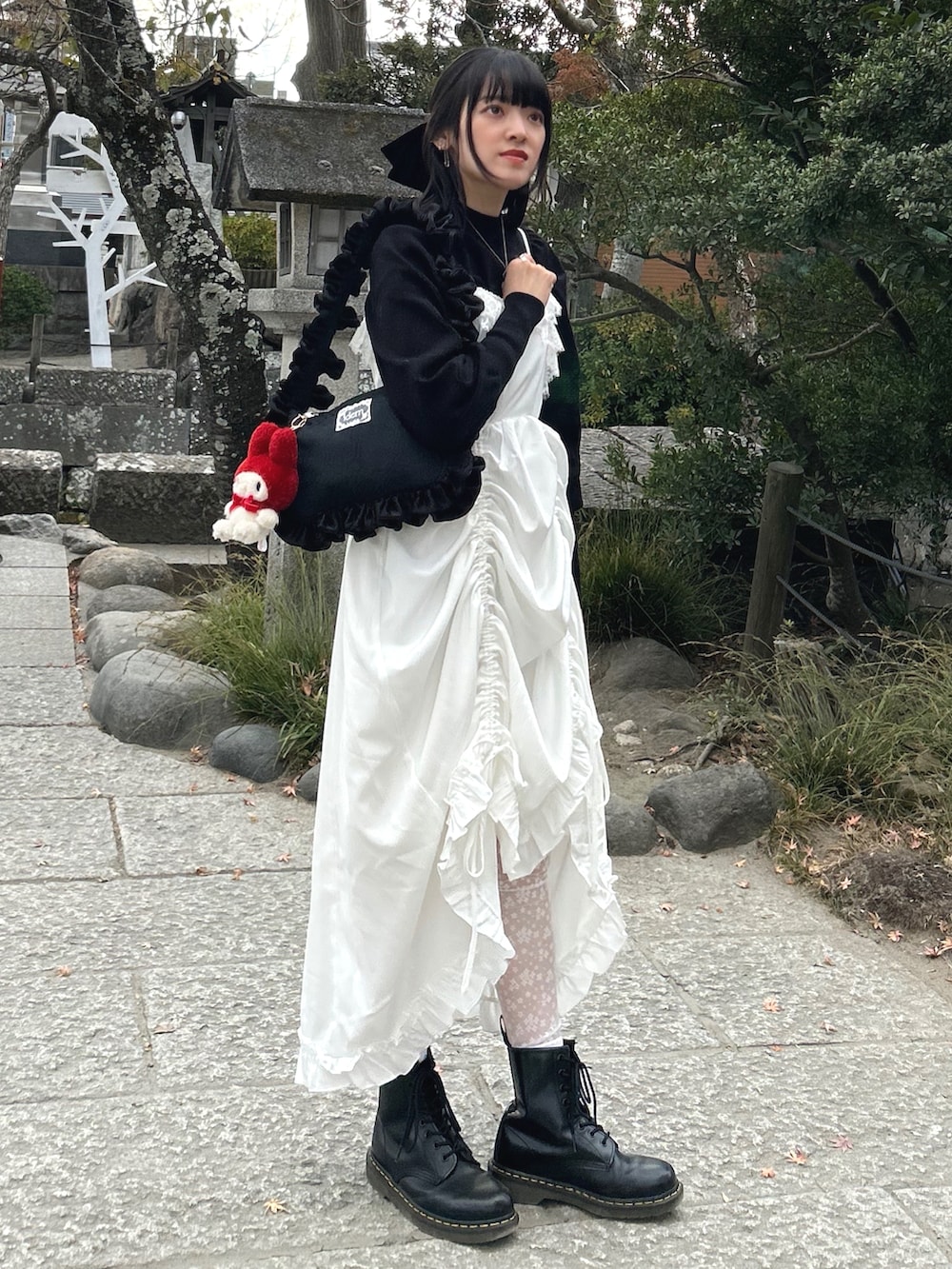 ブラック系のブーツ、ホワイト系のワンピース、ホワイト系のショルダーバッグを着用したレディースの冬コーディネートの4枚目の写真