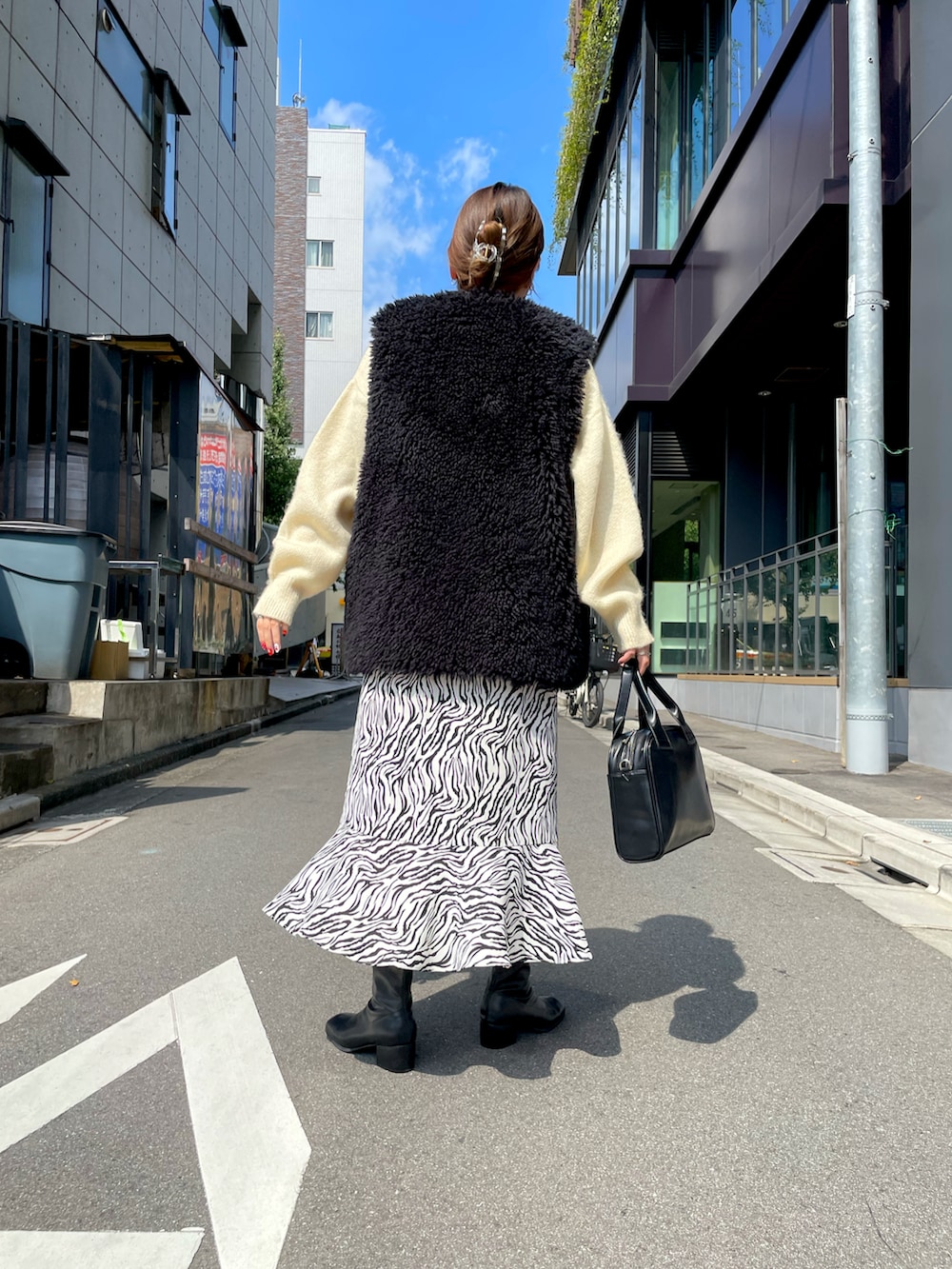 ホワイト系のニット/セーター、ブラック系のベスト、ブラック系のショルダーバッグを着用したレディースの秋コーディネートの3枚目の写真