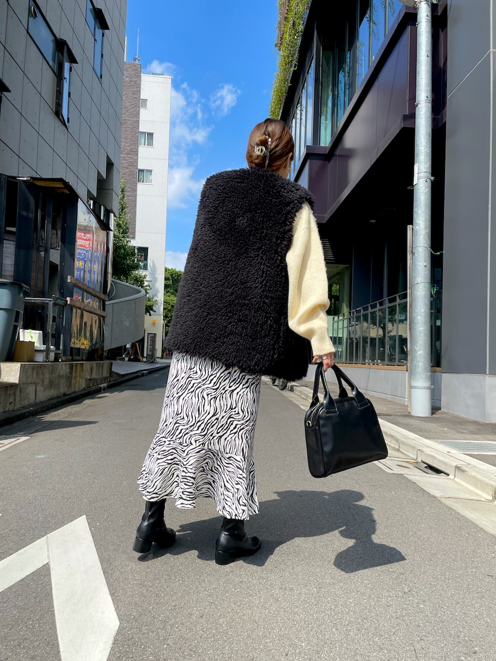 ホワイト系のニット/セーター、ブラック系のベスト、ブラック系のショルダーバッグを着用したレディースの秋コーディネートの2枚目の写真