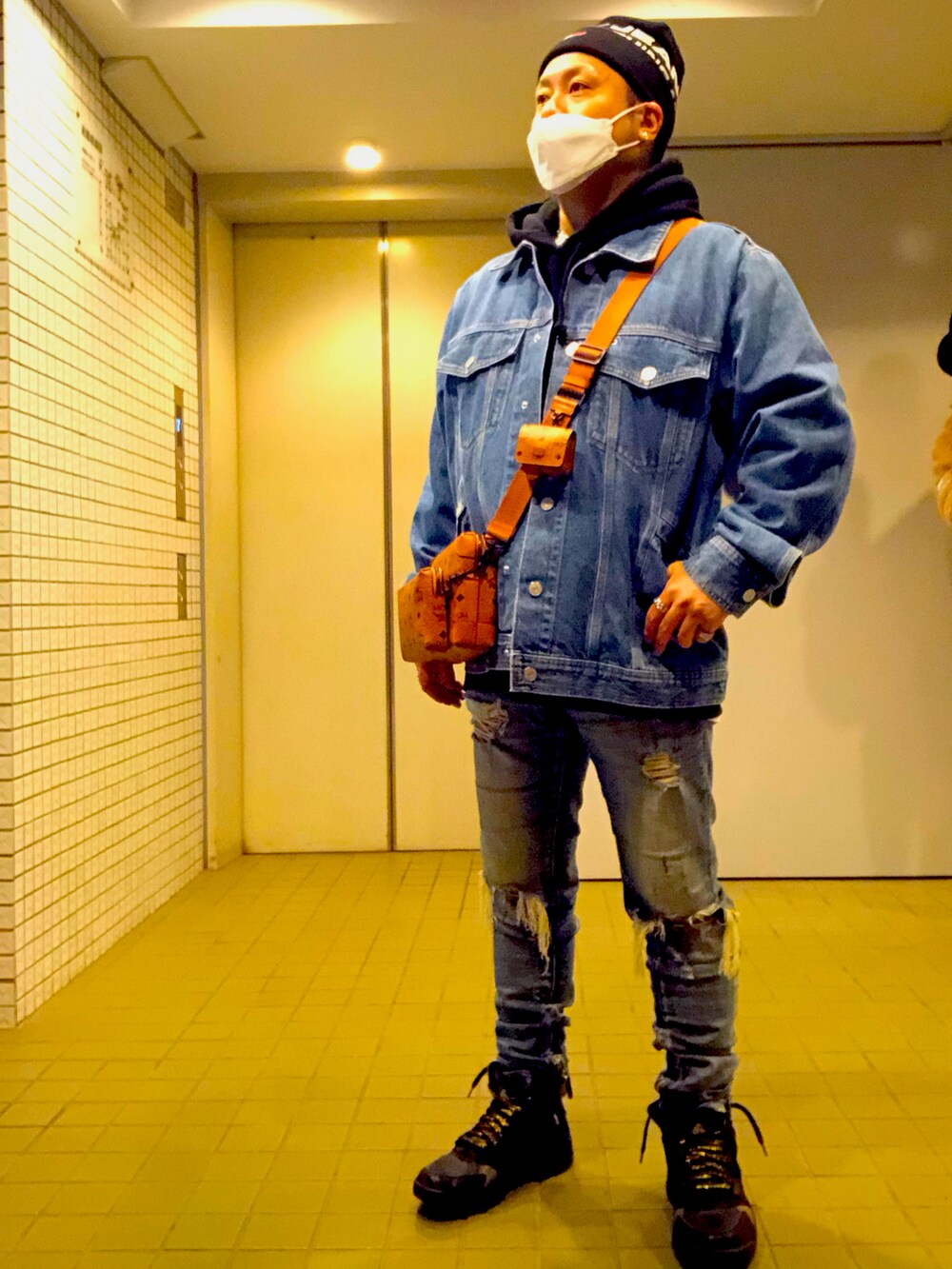 ブルー系のデニムジャケット、ブラウン系のショルダーバッグ、ブルー系のデニムパンツを着用したメンズの冬コーディネートの2枚目の写真