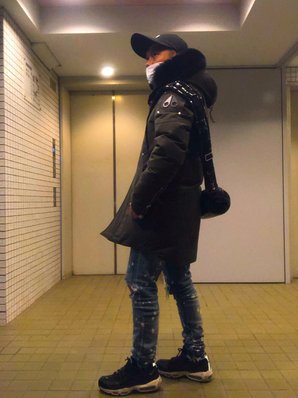 ブラック系のボディバッグ/ウエストポーチ、グリーン系のダウンジャケット/コート、ブルー系のデニムパンツを着用したメンズの冬コーディネートの3枚目の写真