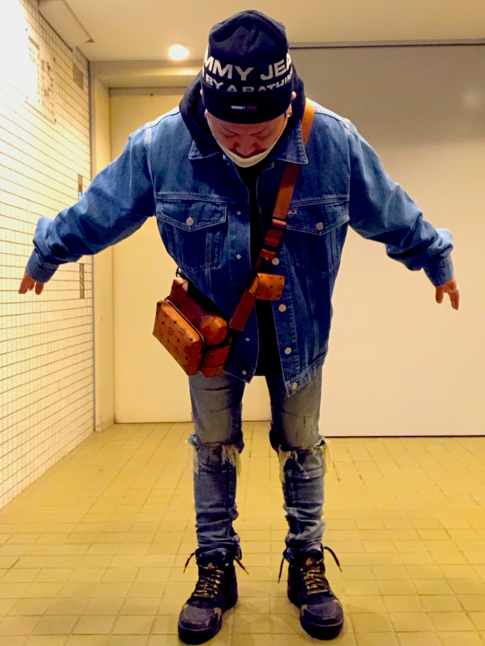 ブルー系のデニムジャケット、ブラウン系のショルダーバッグ、ブルー系のデニムパンツを着用したメンズの冬コーディネートの5枚目の写真