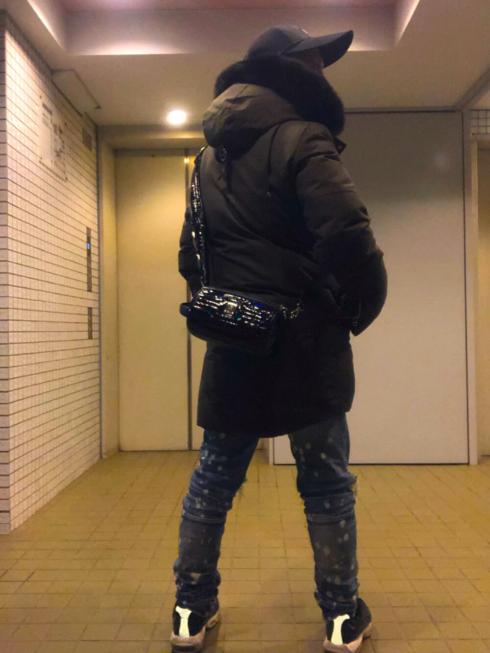 ブラック系のボディバッグ/ウエストポーチ、グリーン系のダウンジャケット/コート、ブルー系のデニムパンツを着用したメンズの冬コーディネートの2枚目の写真