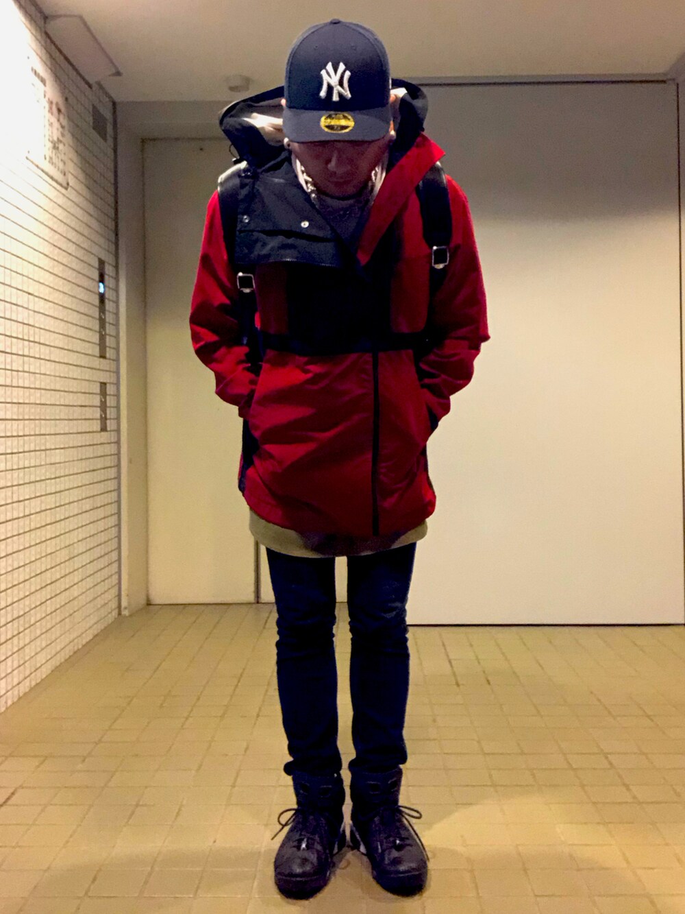 レッド系のブルゾン、ブルー系のデニムパンツ、ブラック系のスニーカーを着用したメンズの秋コーディネートの5枚目の写真