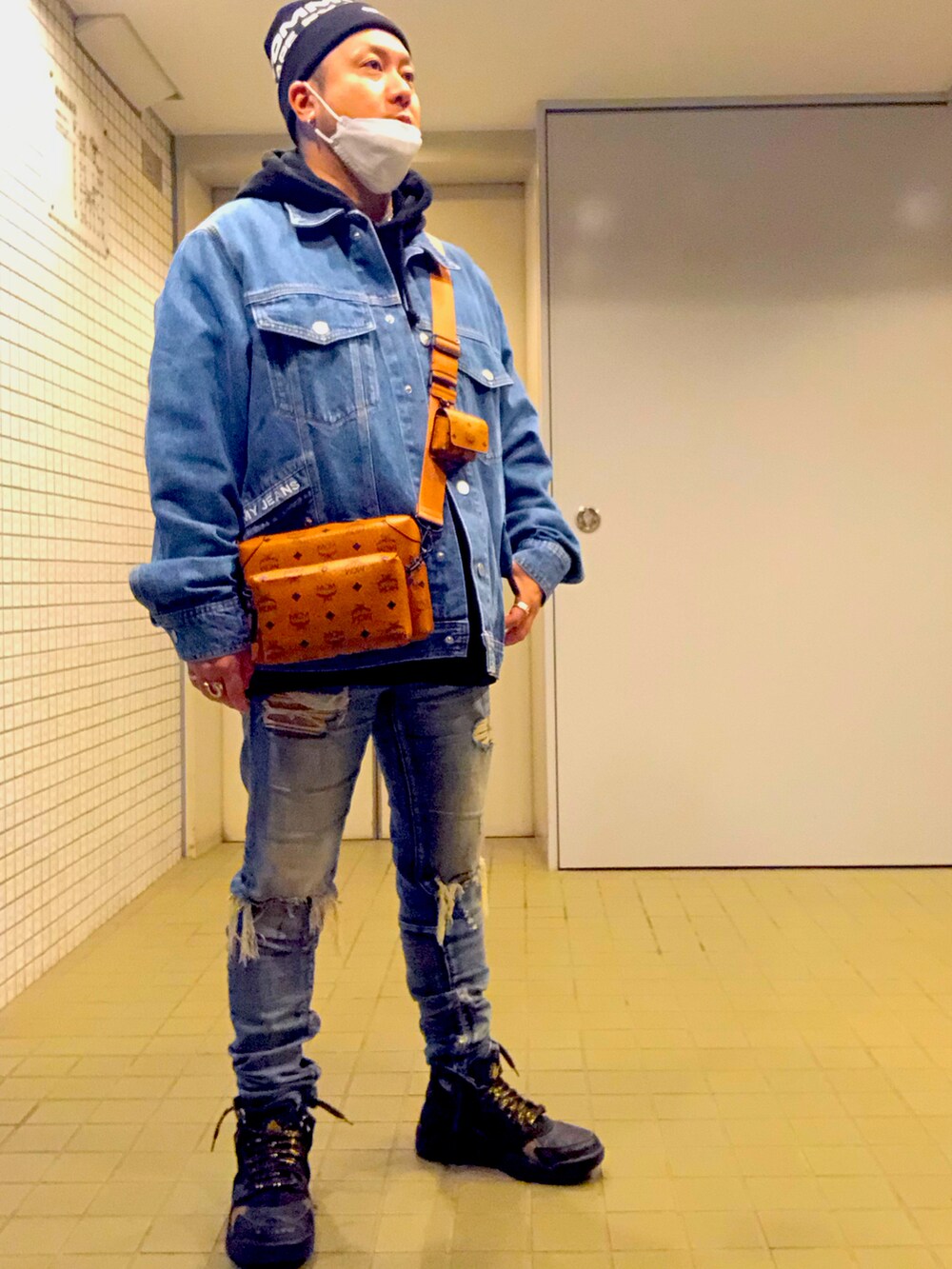 ブルー系のデニムジャケット、ブラウン系のショルダーバッグ、ブルー系のデニムパンツを着用したメンズの冬コーディネートの3枚目の写真