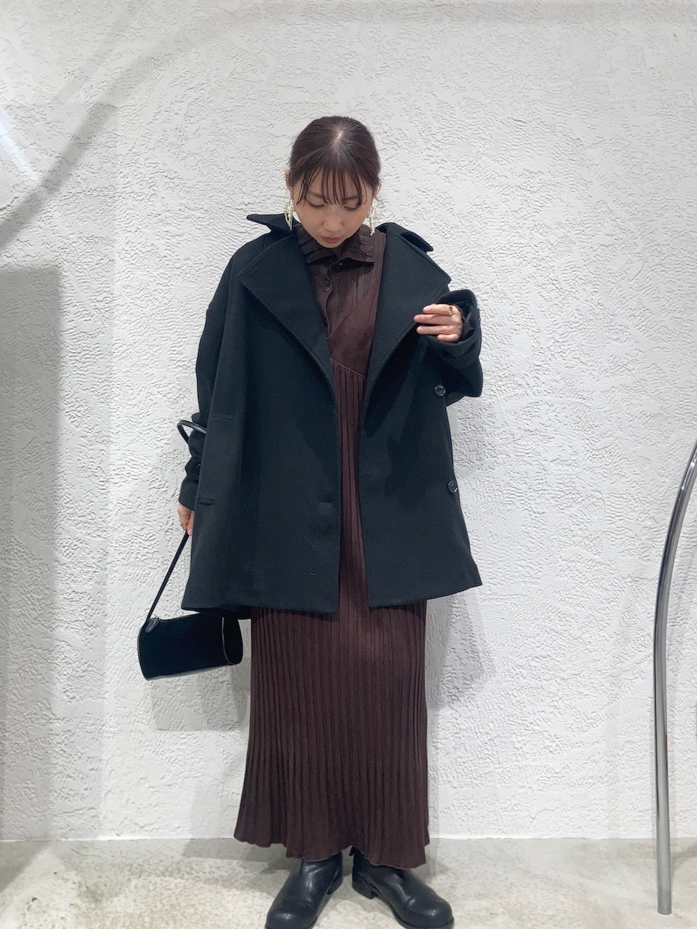 レッド系のワンピース、ブラウン系のニット/セーター、ブラック系のショルダーバッグを着用したレディースの秋コーディネートの2枚目の写真