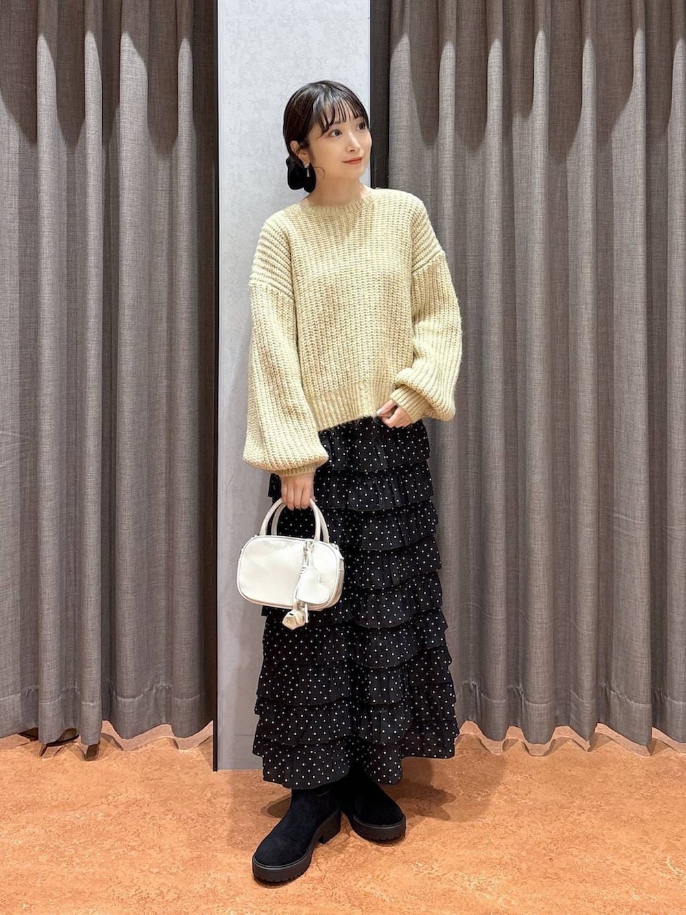 ブラウン系のその他アウター、その他のスカート、ホワイト系のボストンバッグを着用したレディースの冬コーディネートの6枚目の写真