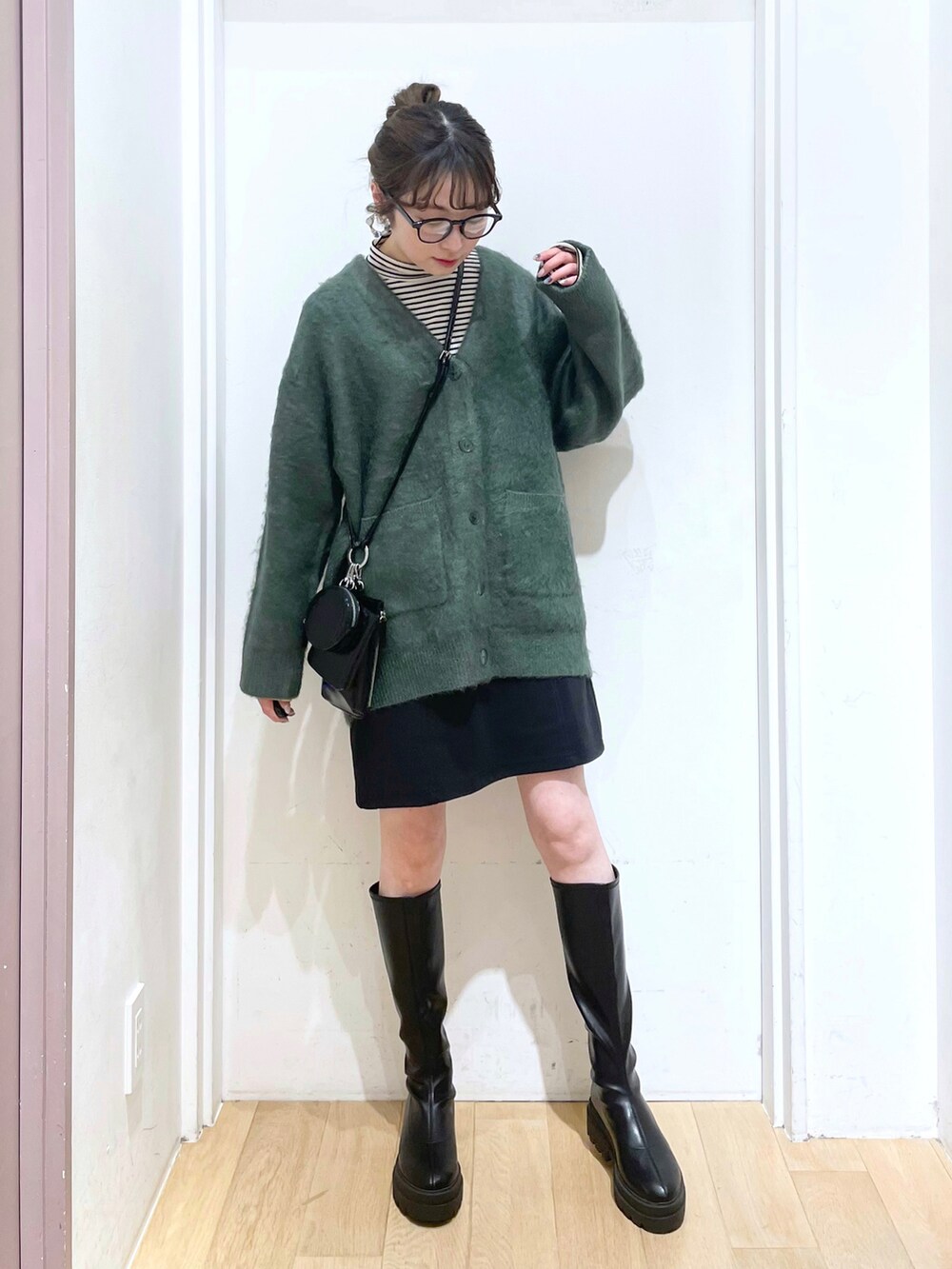 ブラック系のブーツ、ブラック系のスカート、ブラック系のショルダーバッグを着用したレディースの冬コーディネートの2枚目の写真