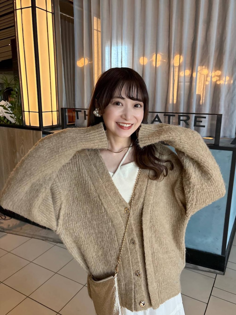 ゴールド系のショルダーバッグ、ブラウン系のローファー、ホワイト系のスカートを着用したレディースの春コーディネートの2枚目の写真