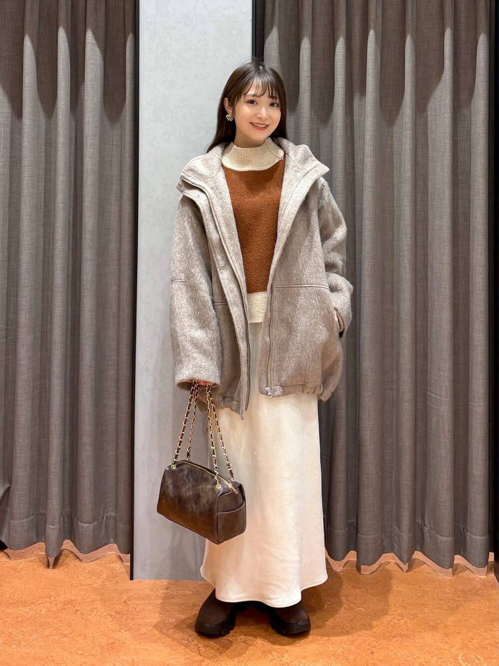 ブラウン系のブーツ、ホワイト系のスカート、ホワイト系のその他アウターを着用したレディースの冬コーディネートの2枚目の写真