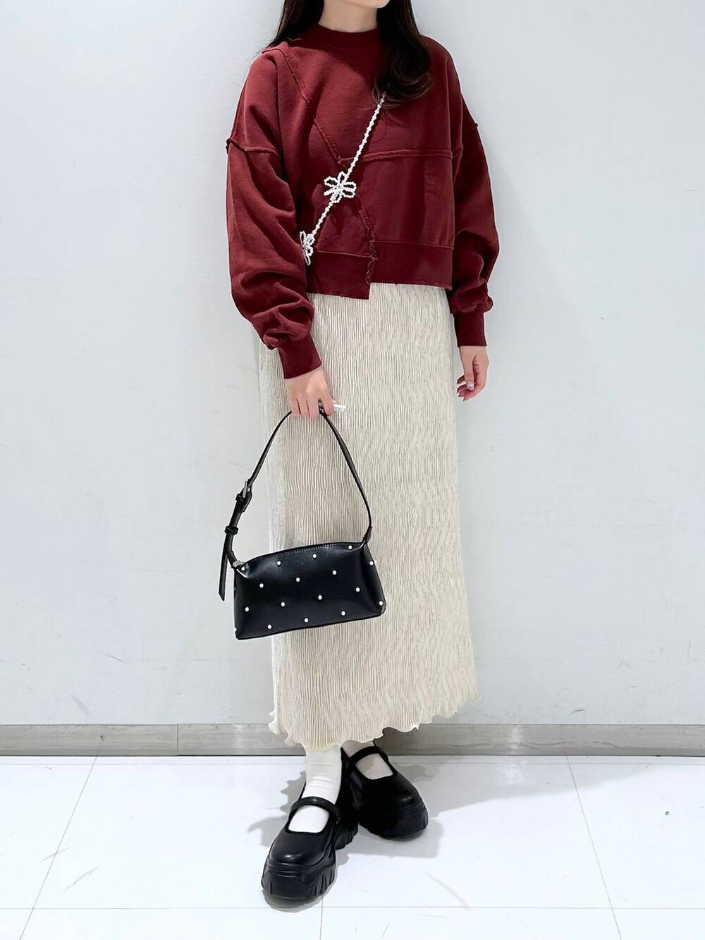 ブラック系のスニーカー、ホワイト系のスカート、ブラック系のショルダーバッグを着用したレディースの秋コーディネートの2枚目の写真