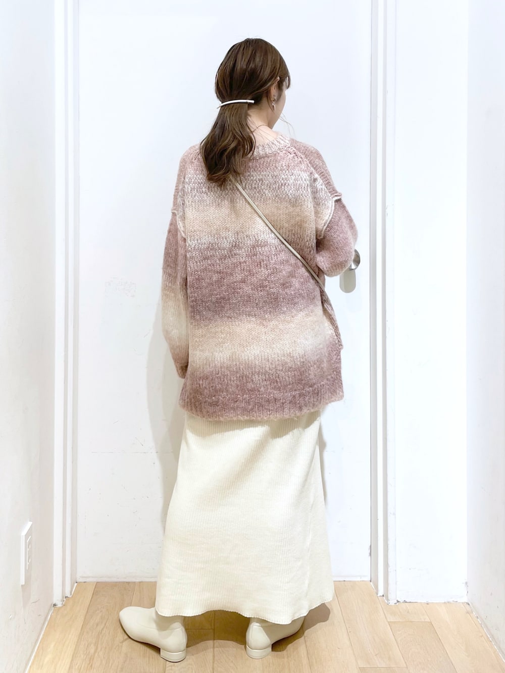 ピンク系のニット/セーター、ホワイト系のショルダーバッグ、ホワイト系のスカートを着用したレディースの秋コーディネートの2枚目の写真