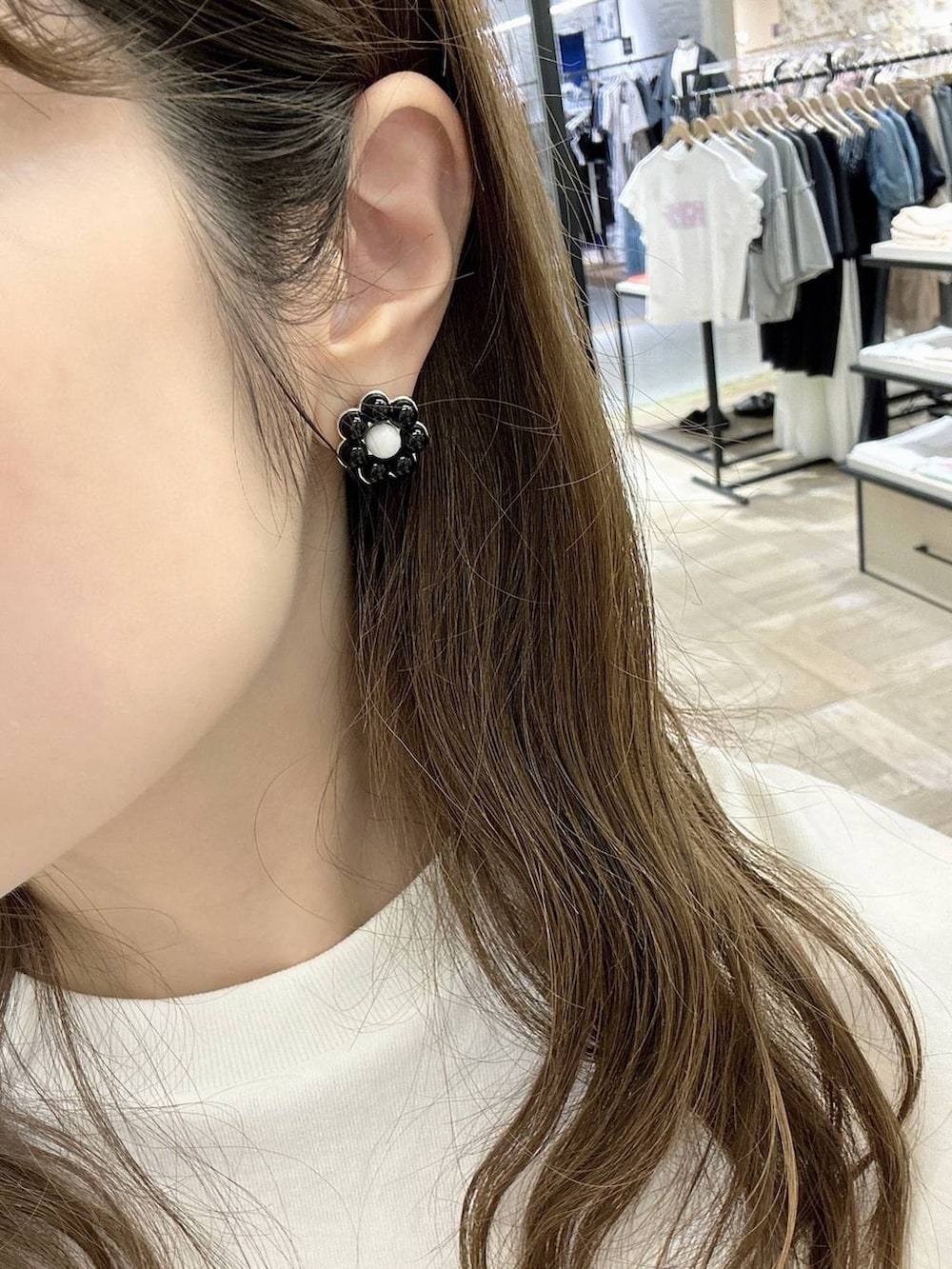 ベージュ系のスマホグッズ、ブラック系のイヤリングを着用したレディースの夏コーディネートの3枚目の写真