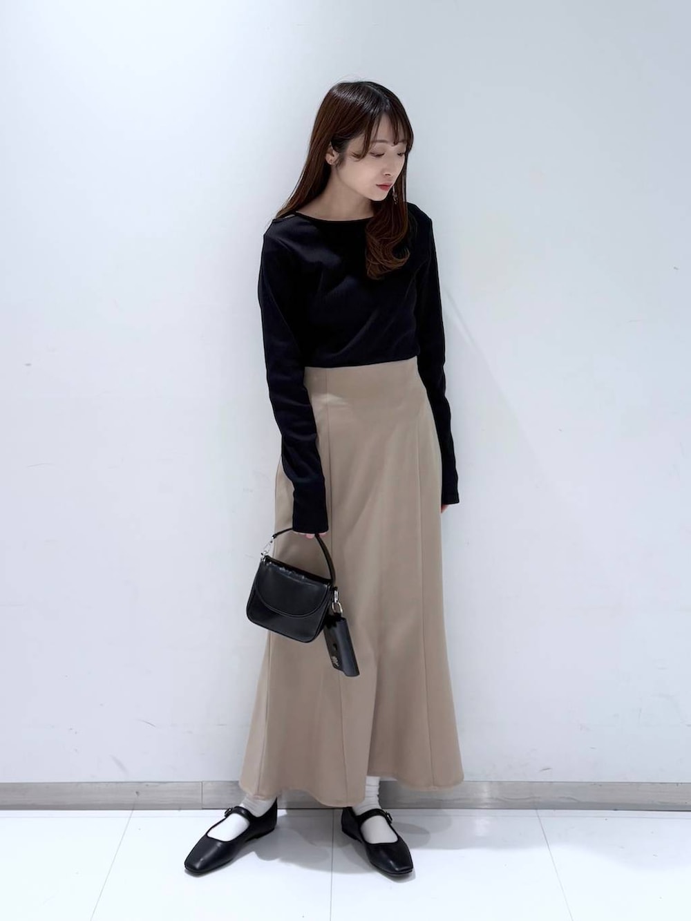 ブラック系のバレエシューズ、ブラック系のショルダーバッグ、ベージュ系のスカートを着用したレディースの冬コーディネートの2枚目の写真