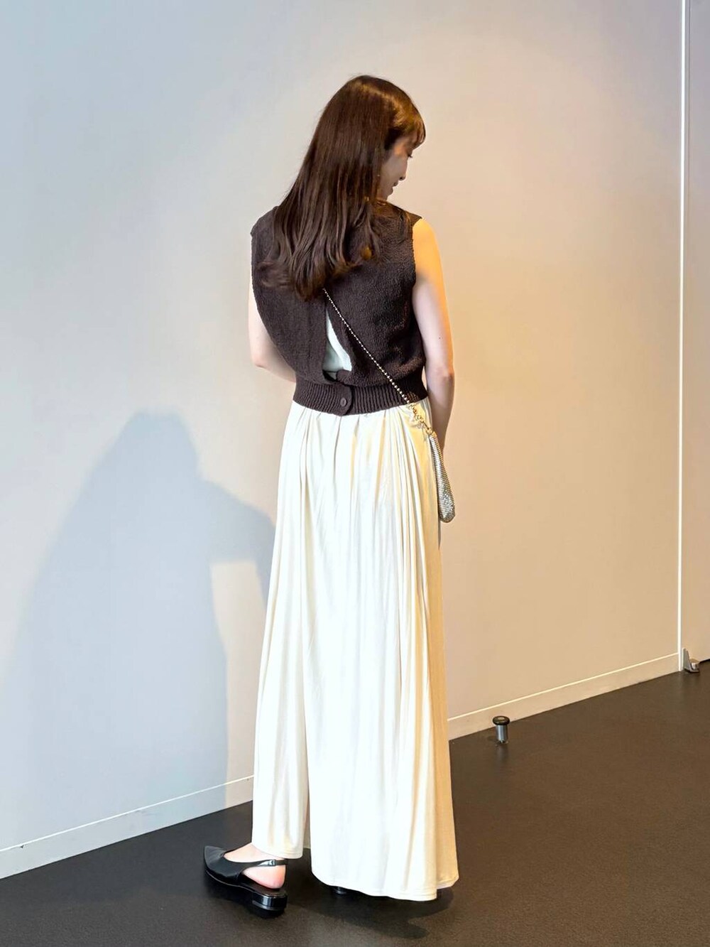 ゴールド系のショルダーバッグ、ブラック系のパンプス、ブラウン系のニット/セーターを着用したレディースの夏コーディネートの4枚目の写真